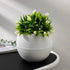 A white spherical planter filled with artificial green foliage and white tulip-like flowers.